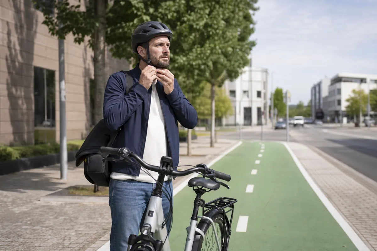 Ebike helmet laws explained with an electric bike rider fastening a helmet before a city ride